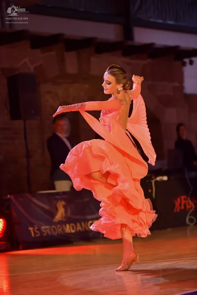 Dancesport competitor: Female dancer: peach-colored latin dress with ruffles and sequin detailing on th