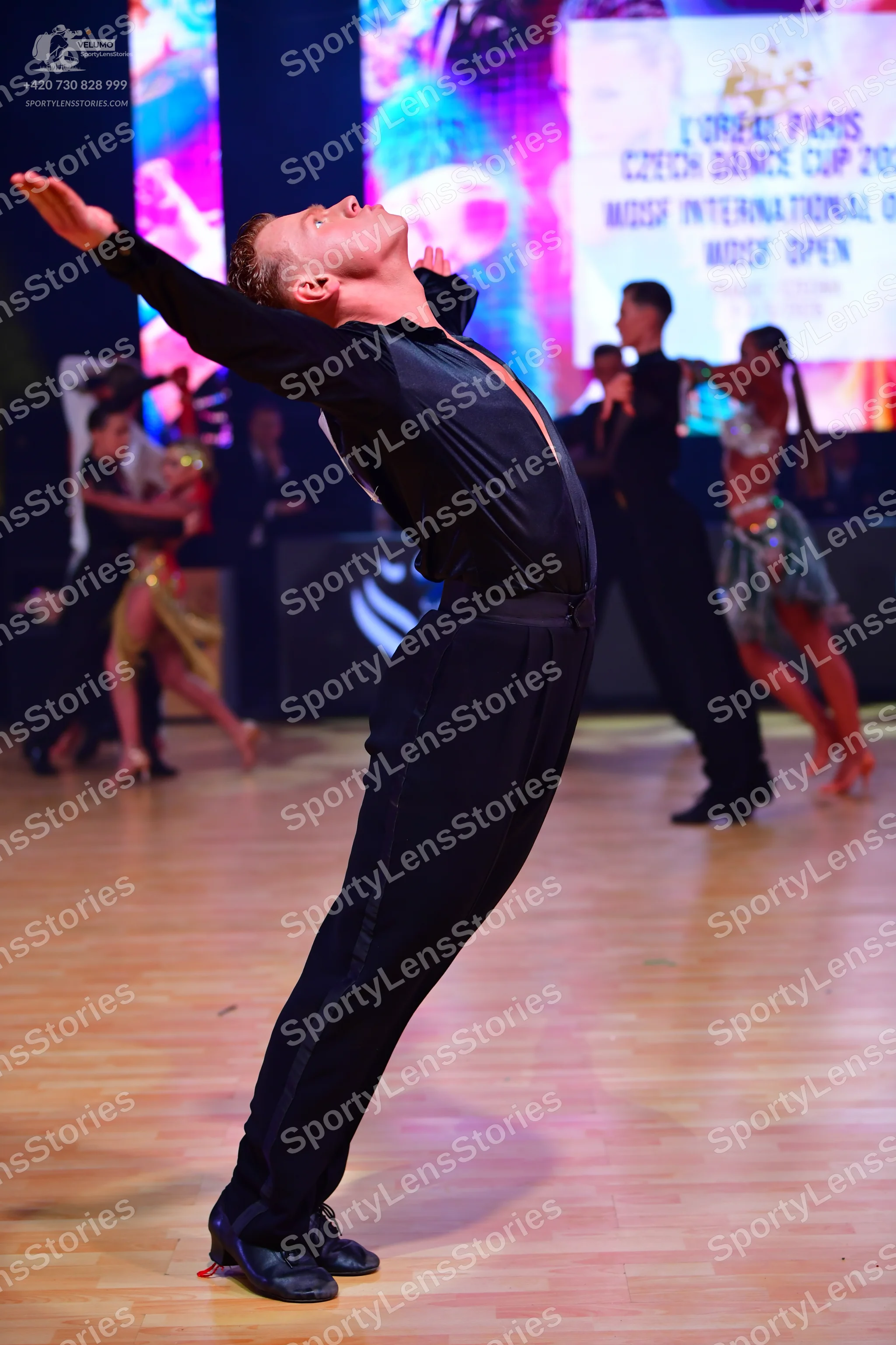 Dancesport competitor: Male dancer (foreground): black long-sleeved shirt and black trousers