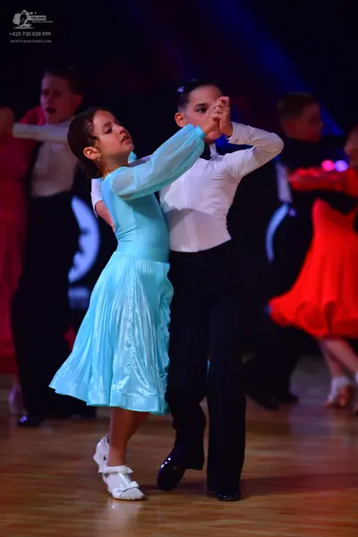 Dancesport competitor: Female dancer in foreground: light blue satin long-sleeved ballroom dress