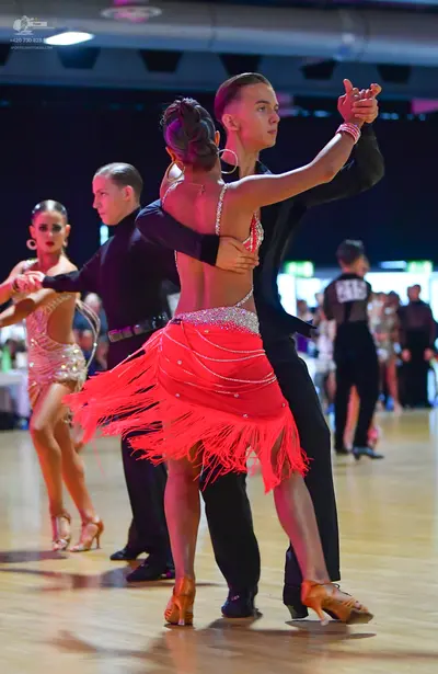 Dancesport competitor #19: Female dancer in foreground: red Latin dress with fringe and silver sequin trim