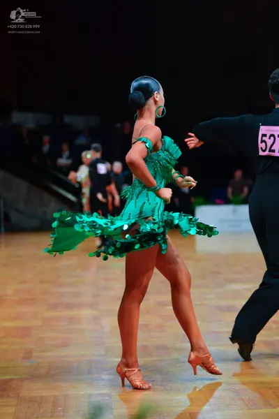 Dancesport competitor: Female dancer: green Latin dress with sequins and fringe