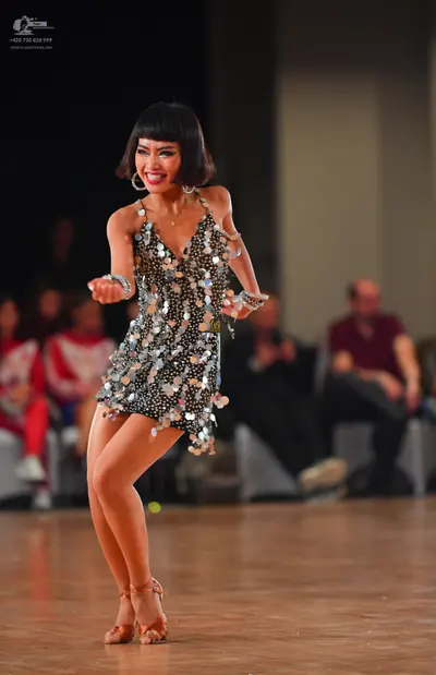 Dancesport competitor: Female dancer: silver latin dress covered in large, reflective sequins, paired w