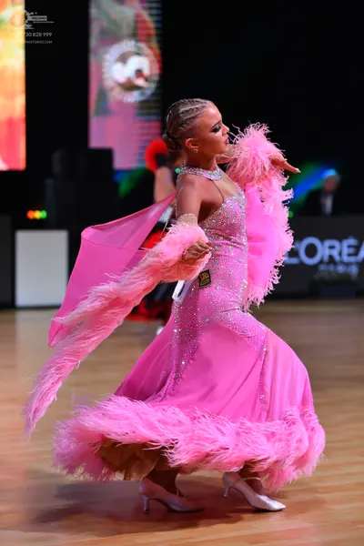 Dancesport competitor: Female dancer: bright pink ballroom gown with heavy rhinestone embellishments an