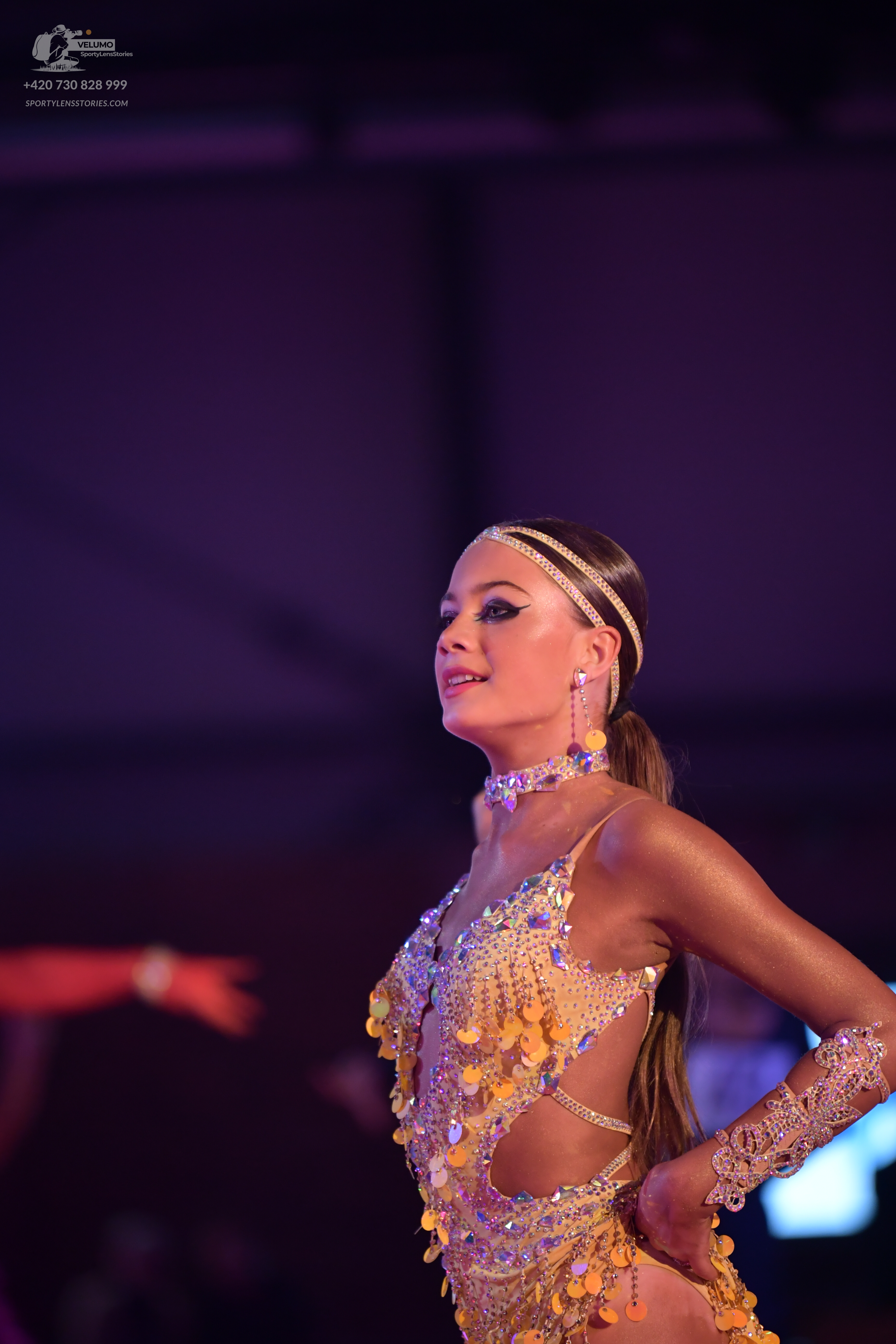 Dancesport competitor: Female dancer: gold Latin dance costume heavily embellished with sequins and rhi
