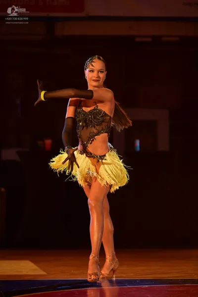 Dancesport competitor: Female dancer: black latin dress with sequins and lace, featuring a yellow fring