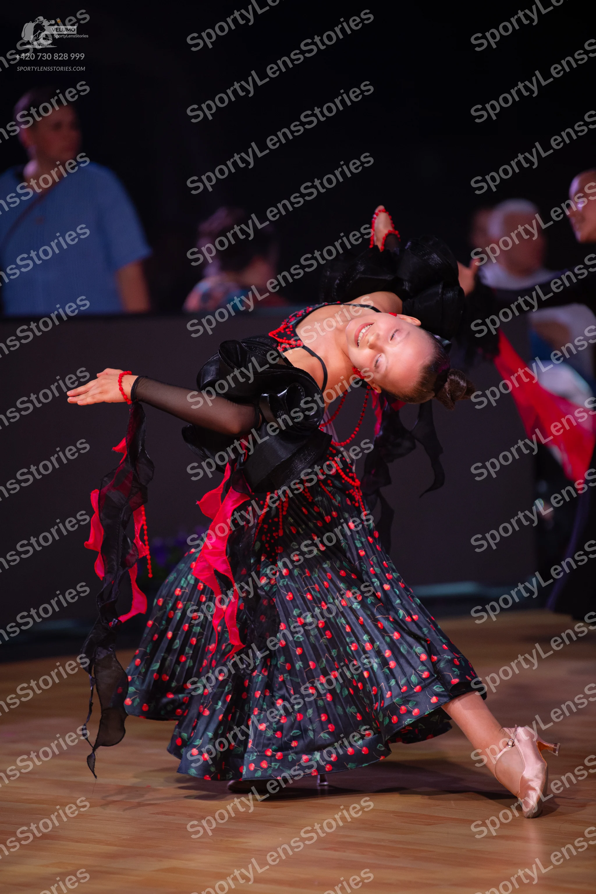 Dancesport competitor: Female dancer: Black Latin dance dress with red polka dots, featuring black ruff