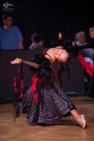 Dancesport competitor: Female dancer: Black Latin dance dress with red polka dots, featuring black ruff