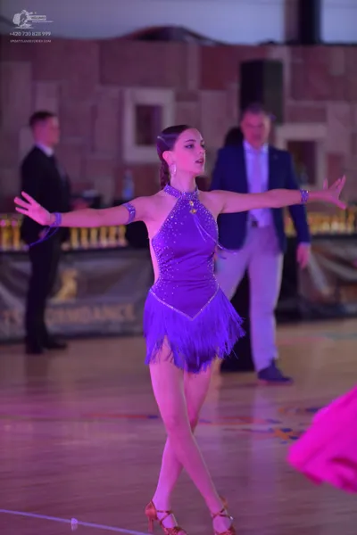 Dancesport competitor: Female dancer: purple latin dress with rhinestones on the bodice and a fringed s