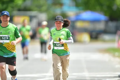 Marathon runner #5274, #5257: Runner 1: green jersey with yellow/orange stripes, black shorts, black compressi