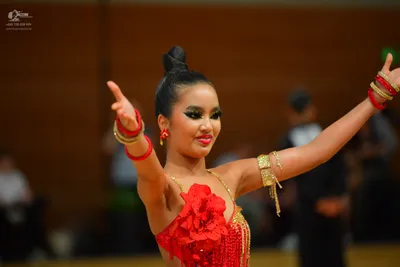 Dancesport competitor: Female dancer: red latin dress with large red fabric flowers, red fringe, and go
