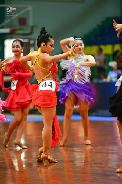 Dancesport competitor #44: Female**

*   **Color:** Primarily Red
*   **Fabric:** Satin (appears to be a gl