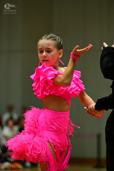 Dancesport competitor: Female dancer: bright pink latin dance dress with large ruffles and long fringe,