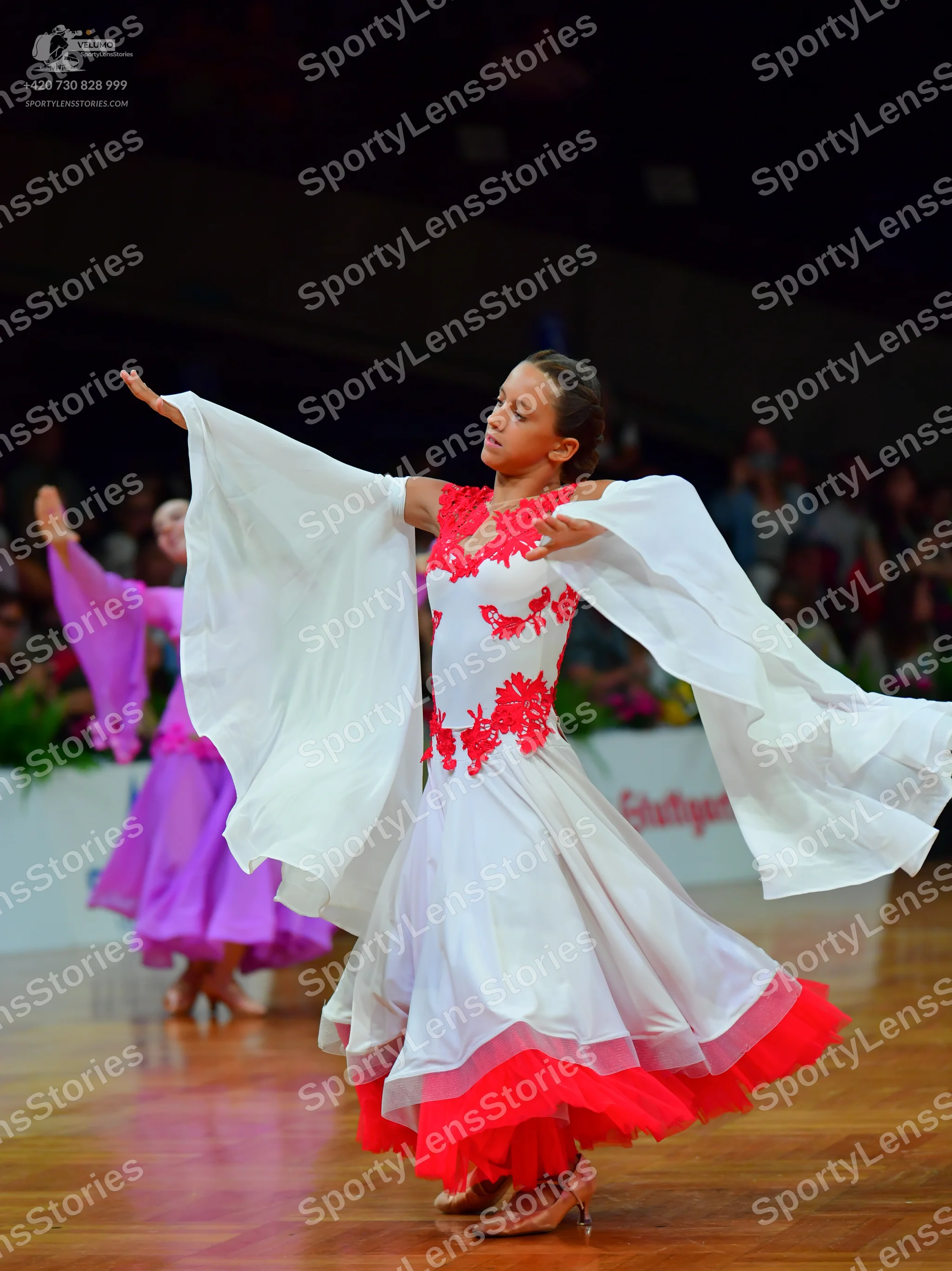 Dancesport competitor: Female dancer in foreground: white ballgown with red lace bodice and a red ruffl