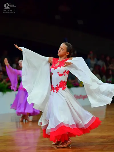 Dancesport competitor: Female dancer in foreground: white ballgown with red lace bodice and a red ruffl