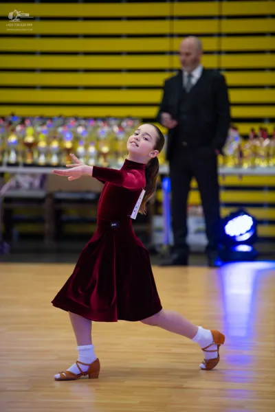 Dancesport competitor: Male (Background Figure):** Black tail suit with a sequined lapel