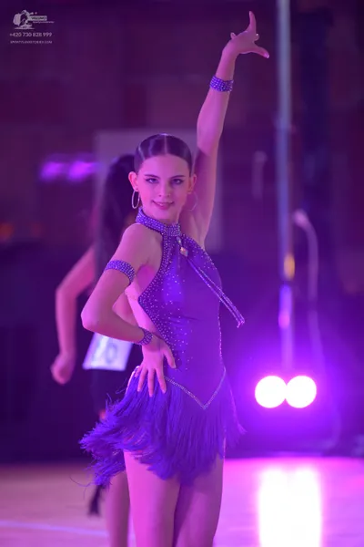 Dancesport competitor: Female dancer: purple latin dress with a sequined bodice, fringe skirt, and matc