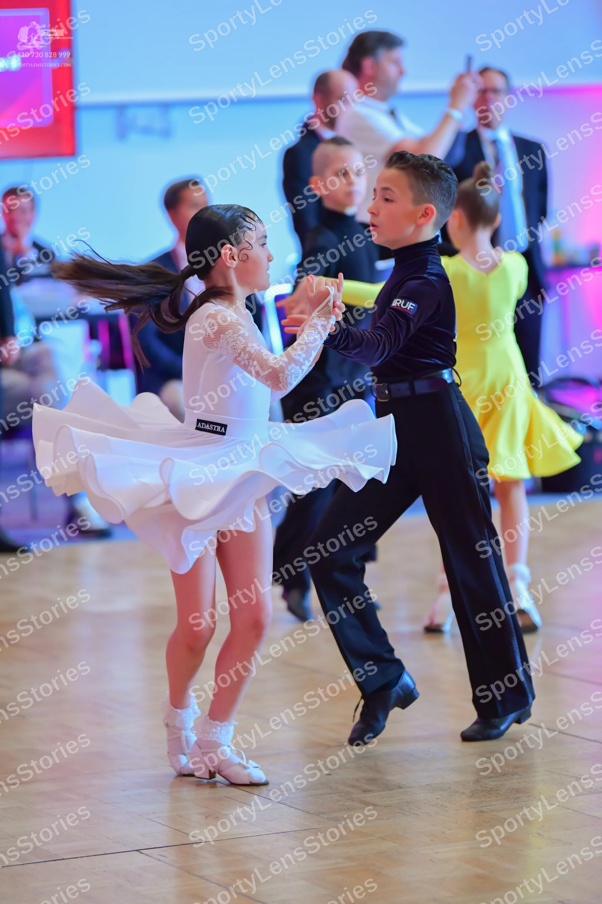 Dancesport competitor: Female dancer: white long-sleeved Latin dress with lace sleeves and a voluminous