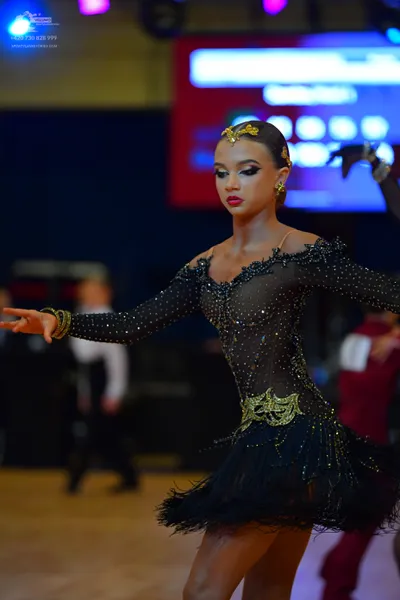 Dancesport competitor: Female dancer: black latin dress with sequins, sheer mesh, and a feathered skirt