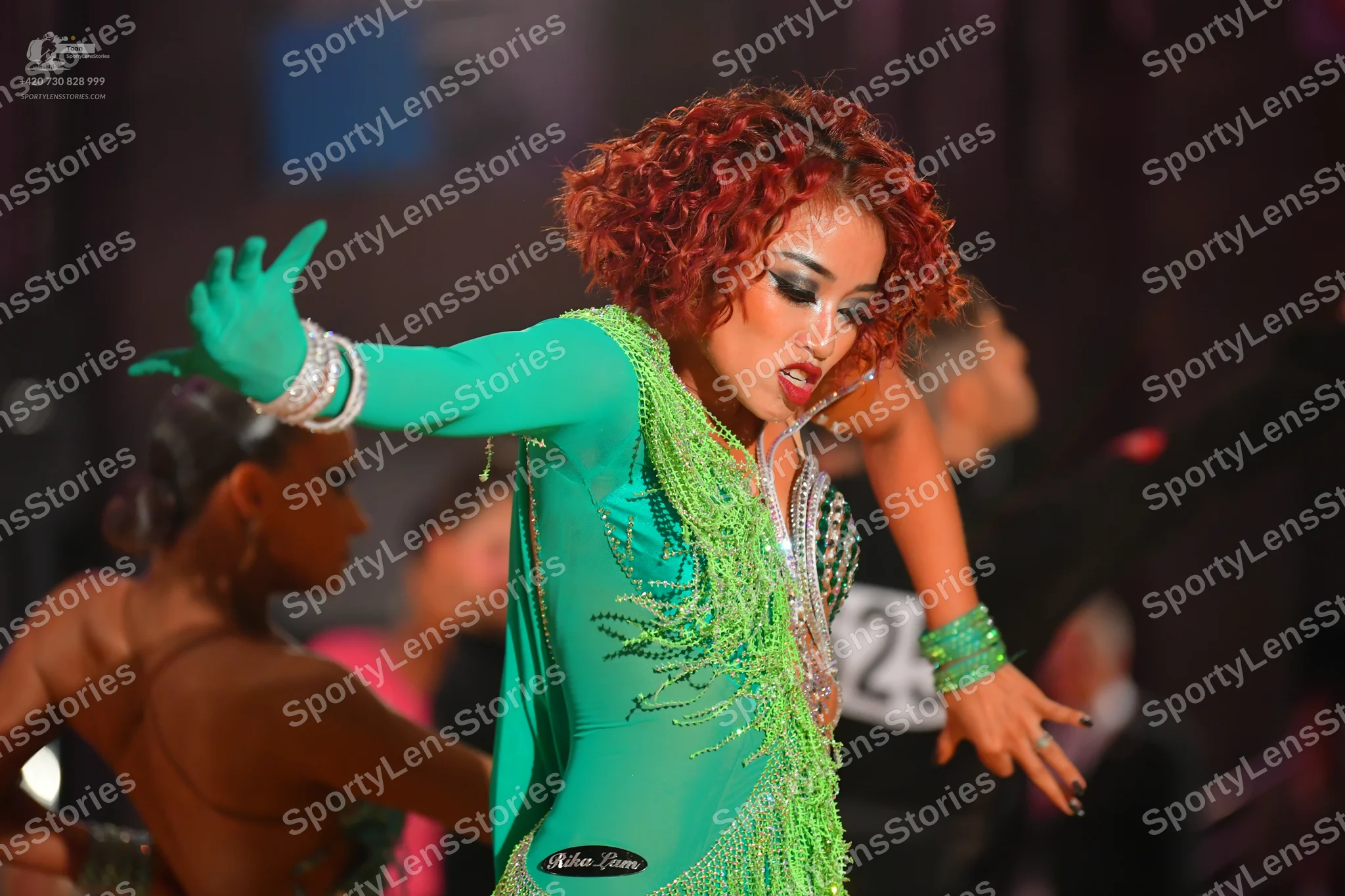 Dancesport competitor #25: Female dancer in foreground: emerald green long-sleeved Latin dress with heavy c