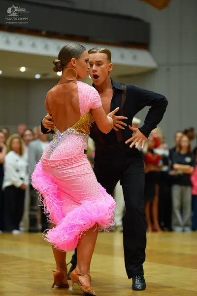 Dancesport competitor: Female dancer: pink latin dress with sequins and pink feathers at the hem, weari