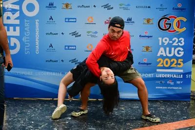 Dancesport competitor: Male dancer: red long-sleeved sweatshirt, black baseball cap, khaki shorts, and 