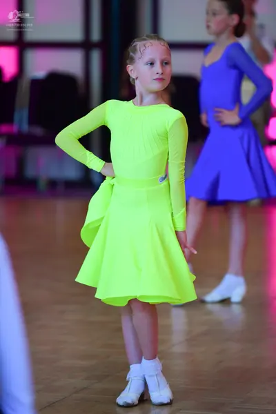 Dancesport competitor: Female dancer: lime green long-sleeved Latin dress with a flared skirt