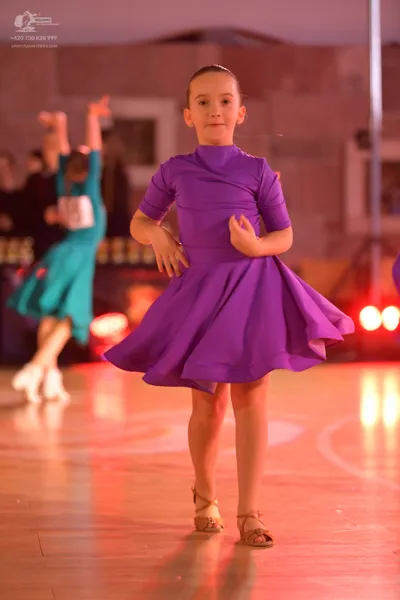 Dancesport competitor: Female dancer in foreground: purple short-sleeved flared dress in a smooth, matt
