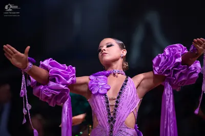 Dancesport competitor: Female dancer: purple latin dress with voluminous ruffled sleeves, a choker-styl