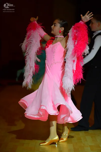 Dancesport competitor: Female dancer: bright pink ballroom dress with large, voluminous pink and light 