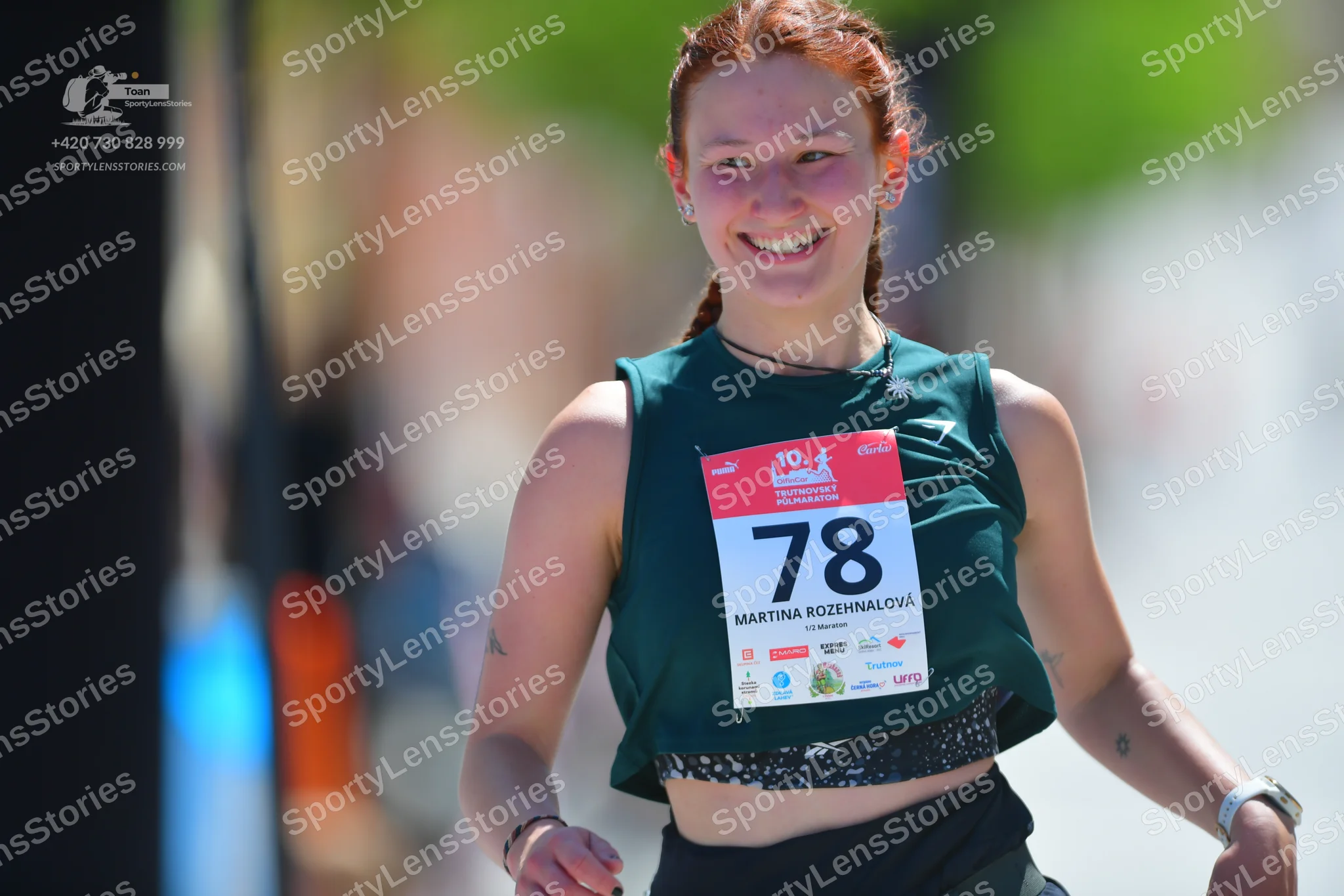 Marathon runner #78: Runner 1: dark green sleeveless crop top, black shorts, dark bracelet on right w