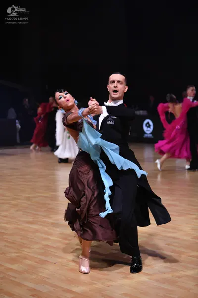 Dancesport competitor: Main female dancer: brown layered/ruffled skirt with a light blue sheer fabric t