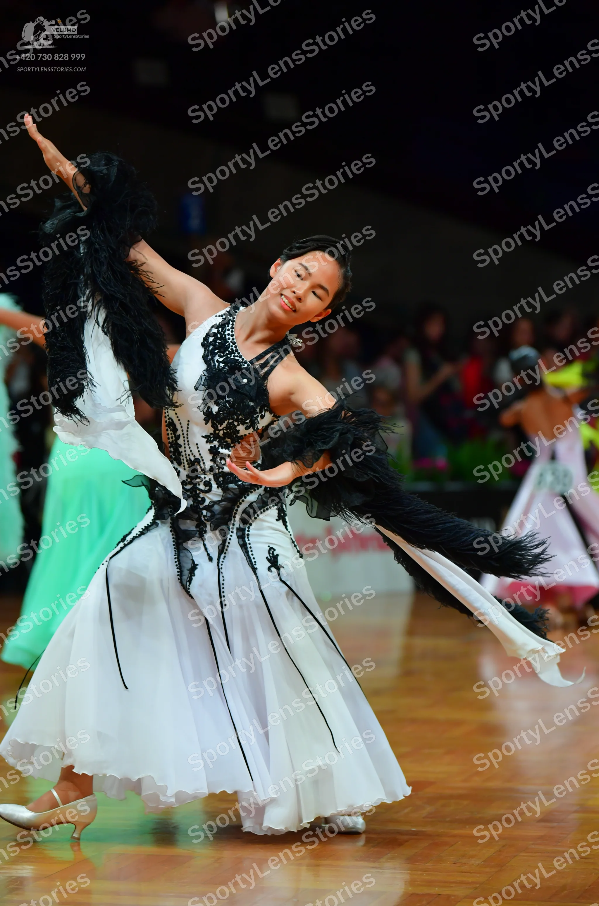 Dancesport competitor: Female dancer: White ballroom dress with black lace and sequin embellishments on