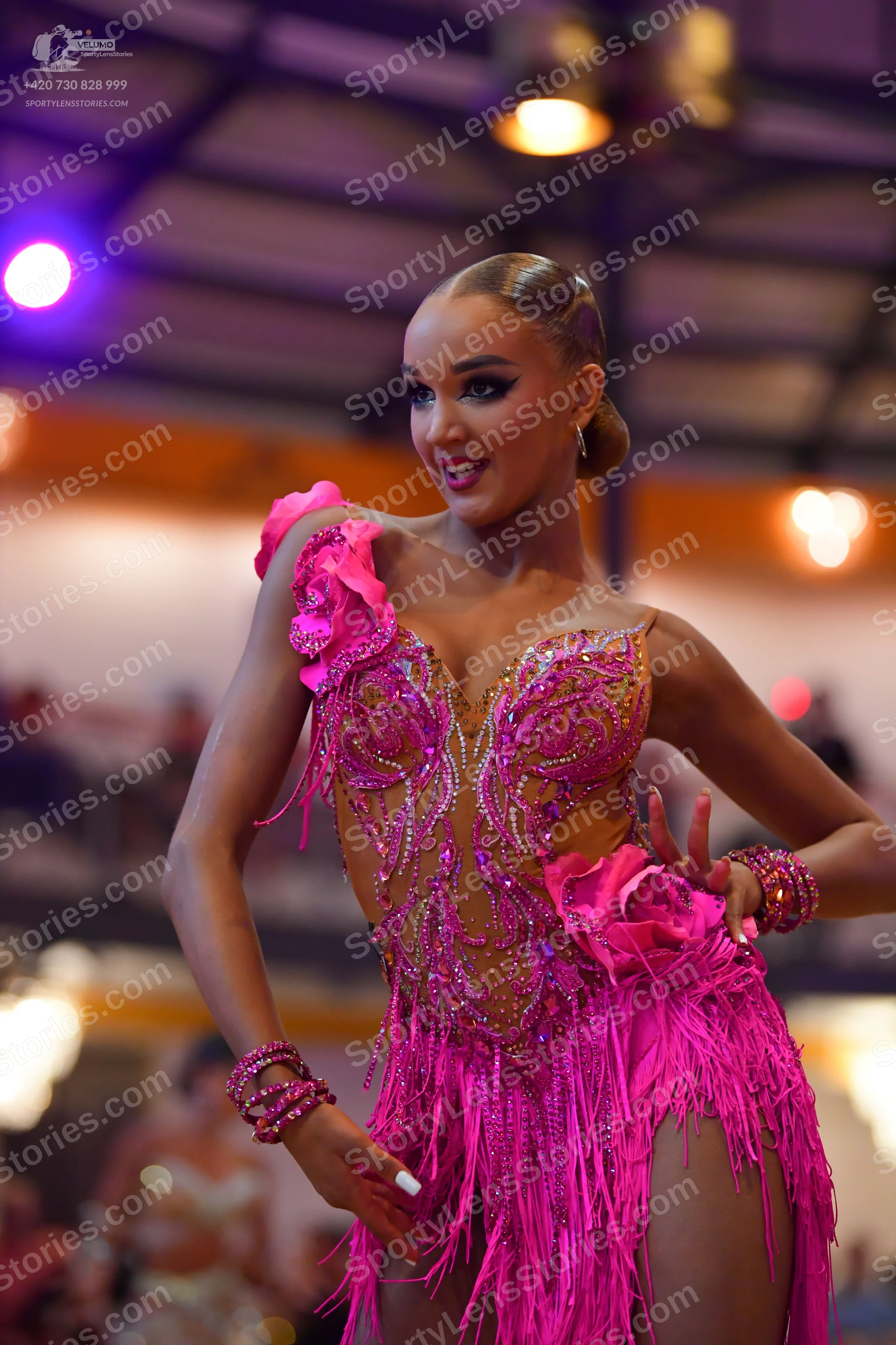 Dancesport competitor: Female dancer: bright pink latin dress with extensive fringe, sequins, and large