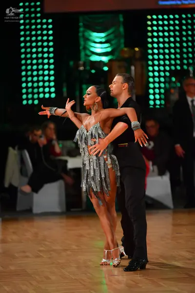Dancesport competitor: Female dancer: silver sequined Latin dress with long fringe, silver high-heeled 