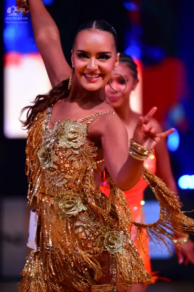 Dancesport competitor: Female dancer 1: gold Latin dress with sequin floral patterns and long gold frin
