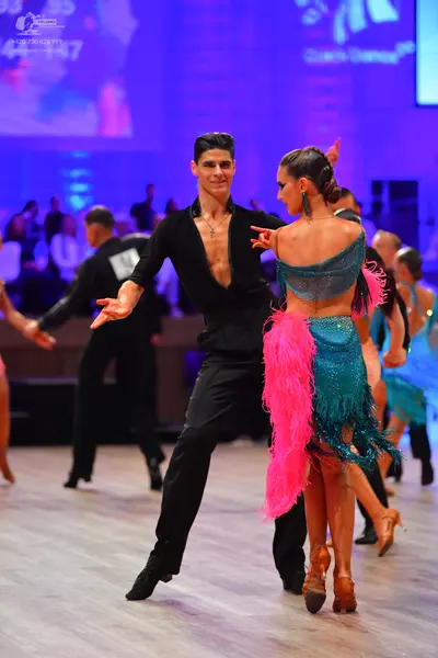 Dancesport competitor: Male dancer: black long-sleeved top with a deep V-neck and black trousers