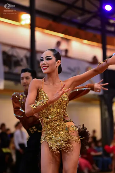 Dancesport competitor: Female dancer: gold sequin latin dress with armbands