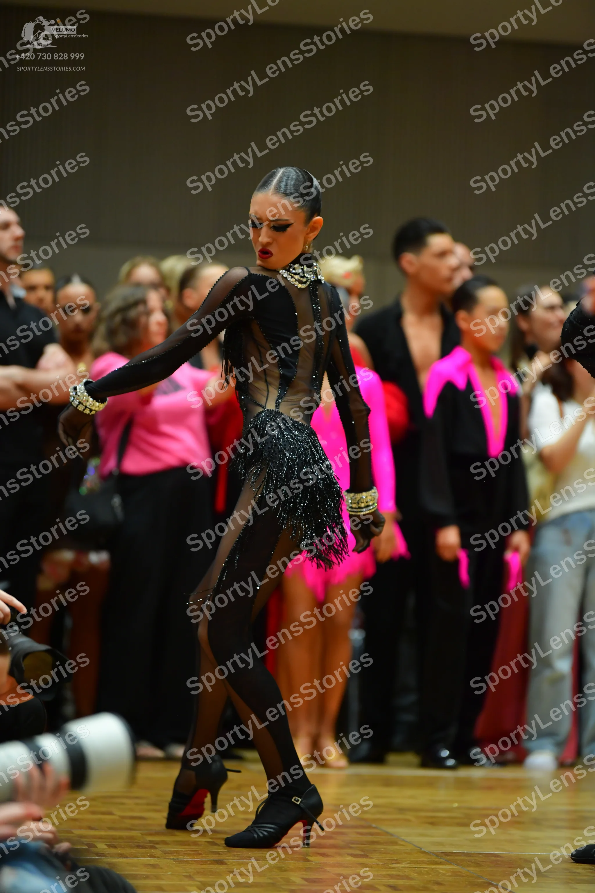 Dancesport competitor: Main female dancer: black Latin dance costume with sheer long sleeves, black seq