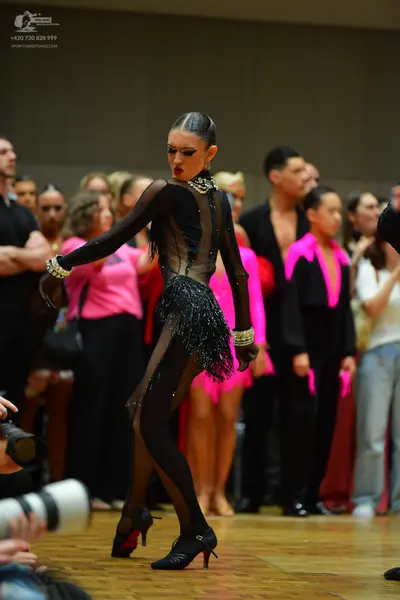 Dancesport competitor: Main female dancer: black Latin dance costume with sheer long sleeves, black seq