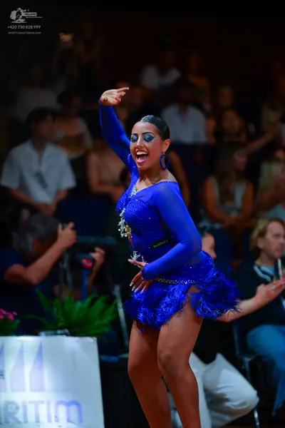 Dancesport competitor: Female dancer: royal blue long-sleeved latin dress with a feathered or fringed s
