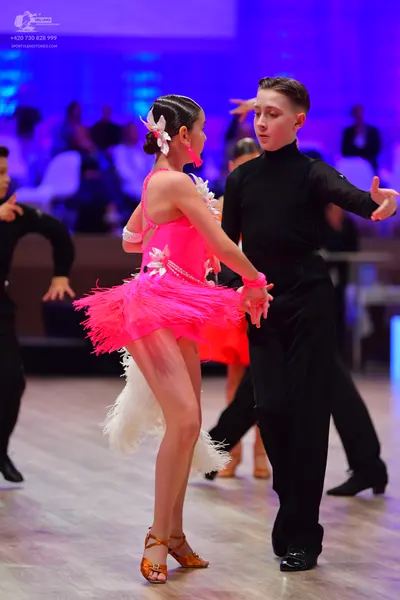 Dancesport competitor: Female dancer: pink latin dress with fringe and white floral/feather accents