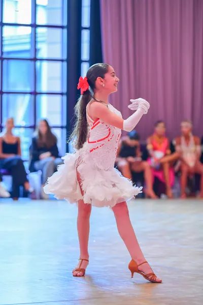 Dancesport competitor: Main dancer: White Latin dance dress with a textured, ruffled skirt and red patt