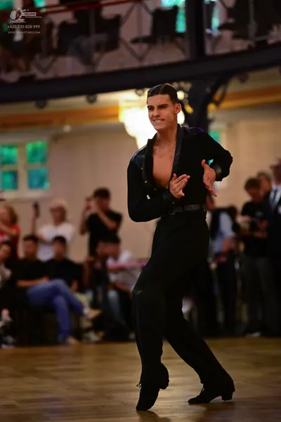 Dancesport competitor: Male dancer: black Latin-style shirt with satin-like lapels and black trousers
