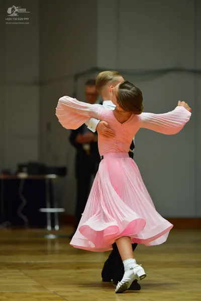 Dancesport competitor: Female dancer: light pink long-sleeved ballroom dress with a pleated skirt and w