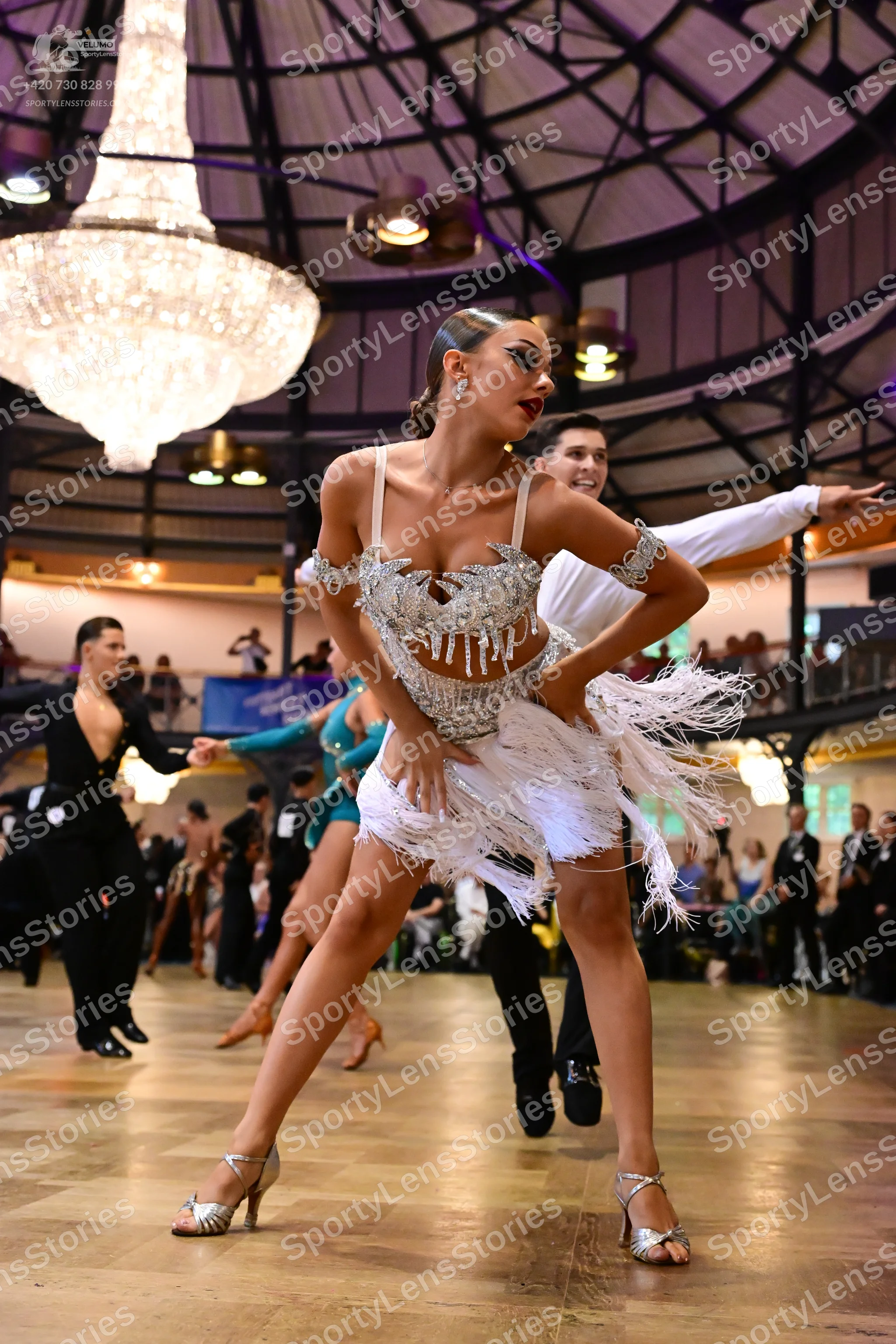 Dancesport competitor: Lead female dancer: silver/white latin dress with sequins, beads, and long white