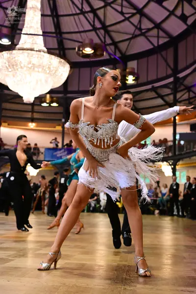 Dancesport competitor: Lead female dancer: silver/white latin dress with sequins, beads, and long white