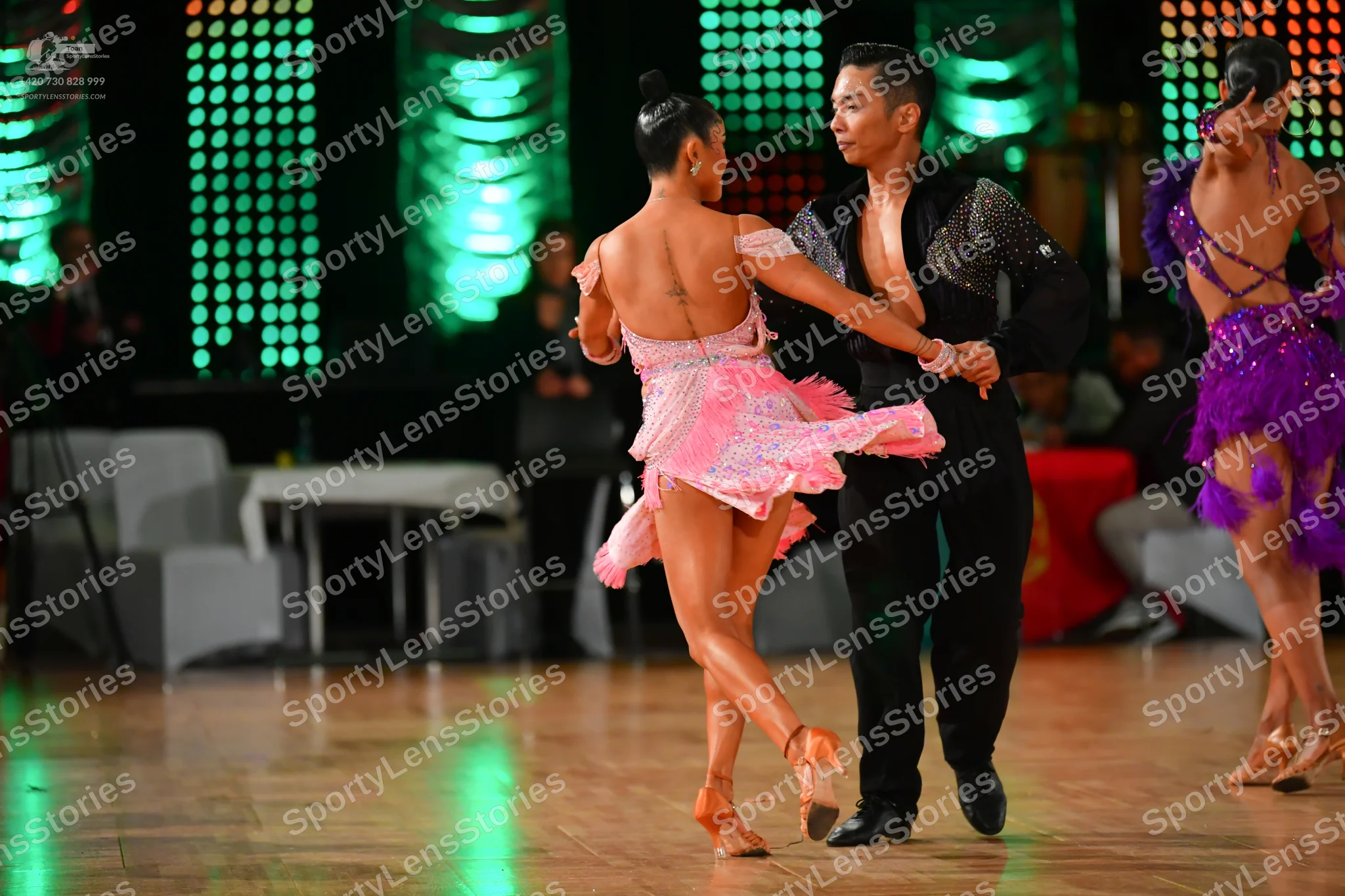 Dancesport competitor: Female dancer in center: light pink/lavender Latin dress with sequins and fringe