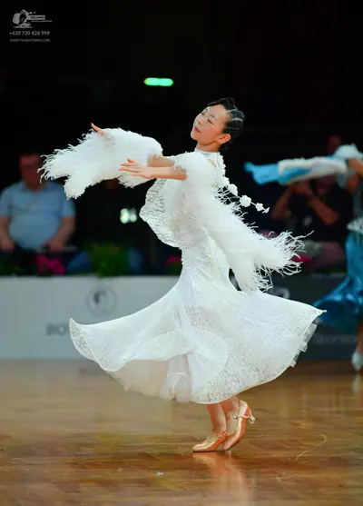 Dancesport competitor: Female dancer: white lace dance dress with large, white, fluffy, feather-like ac