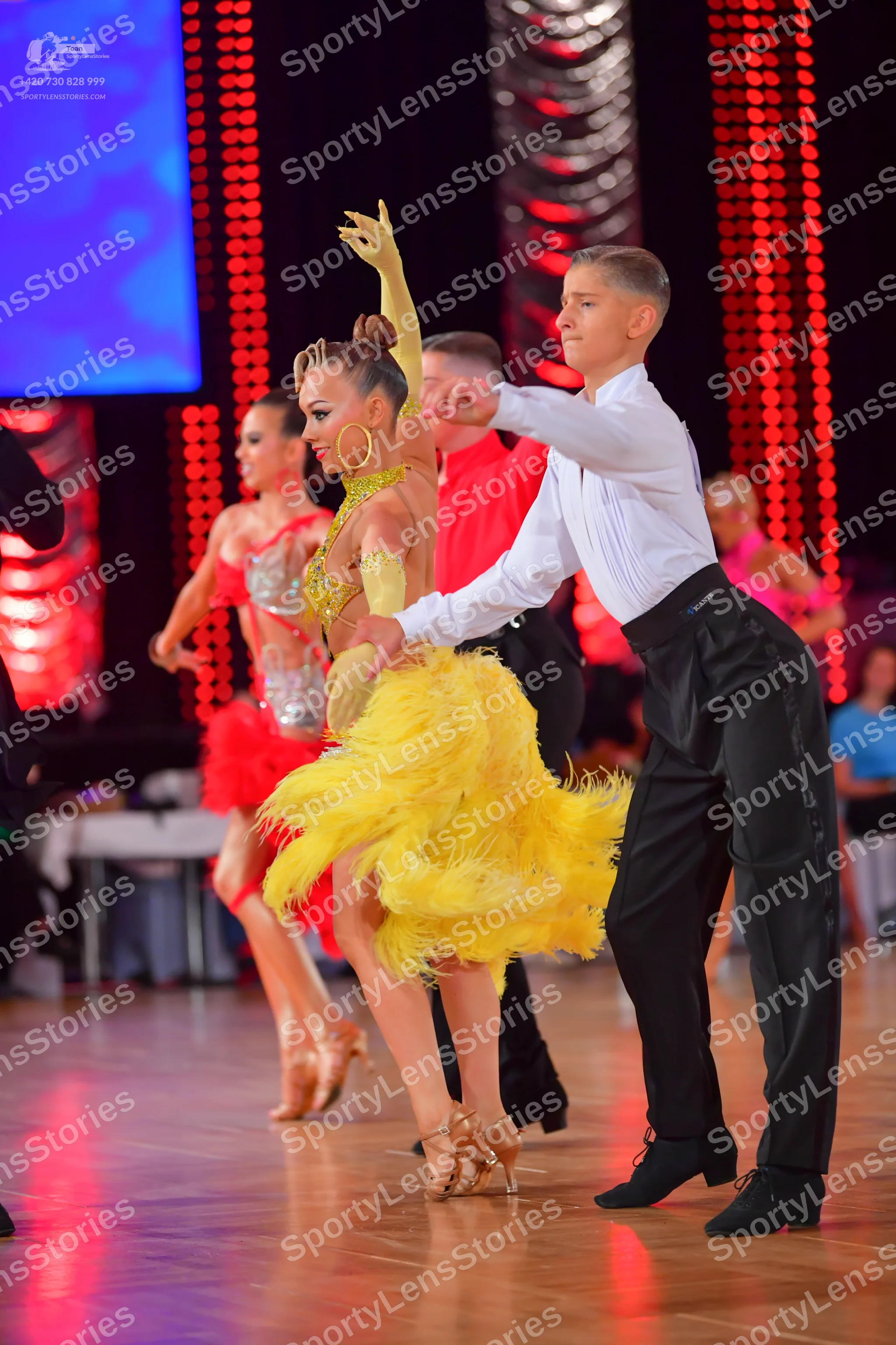 Dancesport competitor: Main female dancer: yellow feathered/fringed Latin dress with a nude-colored, em