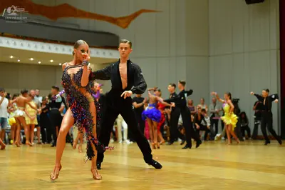 Dancesport competitor: Female dancer in foreground: black and purple latin dress heavily embellished wi
